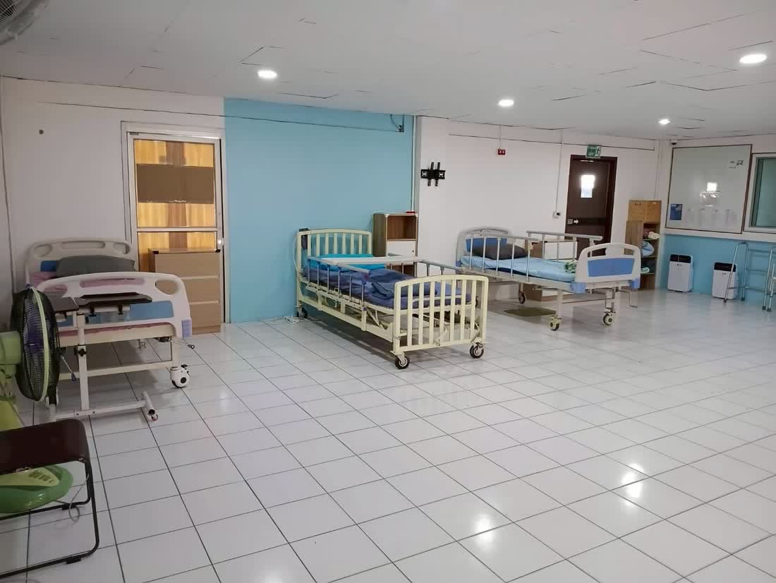 ห้องพักรวมพร้อมเตียงพยาบาลปรับระดับหลายเตียง ตู้เก็บของ และเครื่องฟอกอากาศ